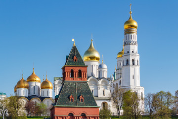 Fototapeta na wymiar Orthodox churches with golden domes against tower of Moscow Kremlin in sunlight. Kremlin is a famous touristic landmark in Moscow center