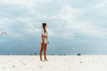 girl on the beach look at flying kites