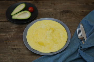 Omelette or omelet and avocado, tomato on the wooden rustic background with tissue napkin, fork and knife. Top view Photo for menu. Food background, pattern, poster. With copy space for text