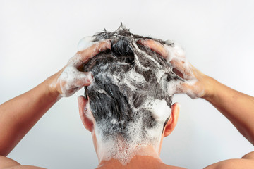 Men's hands wash their hair with shampoo and foam on white background, rear view