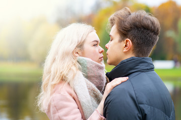Fototapeta premium Lovely brunette guy and pretty girl blonde drink coffee and talking on date. Loving teenagers are happy, smiling, kissing. Teen Love Concept. Outdoor.