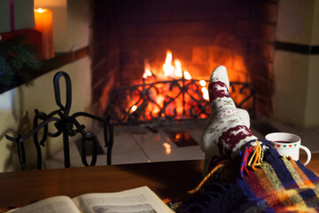 Fototapeta na wymiar Man and woman in warm socks near the fireplace. Cup with a hot drink. Heart.