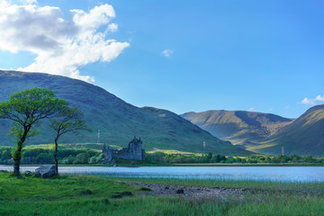 Kilchurn Castle , in the care of Historic Environment Scotland , is a ruined structure on a rocky peninsula at Loch Awe in summer , Argyll and Bute, Scotland