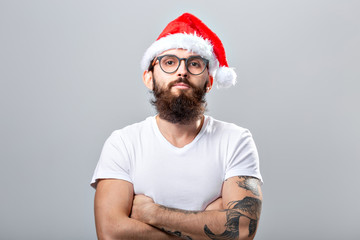 Holidays and people concept - Portrait of a handsome brutal man in Christmas hat. Over grey background.