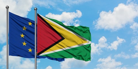 European Union and Guyana flag waving in the wind against white cloudy blue sky together. Diplomacy concept, international relations.
