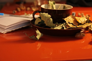 Great, beautiful autumn background. dry autumn oak leaves in a brown mug and on a plate. Nearby lies a notebook. Copy space