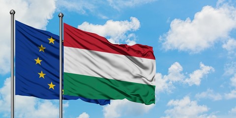 European Union and Hungary flag waving in the wind against white cloudy blue sky together. Diplomacy concept, international relations.
