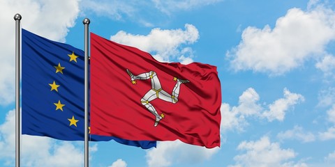European Union and Isle Of Man flag waving in the wind against white cloudy blue sky together. Diplomacy concept, international relations.