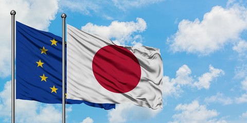 European Union and Japan flag waving in the wind against white cloudy blue sky together. Diplomacy...