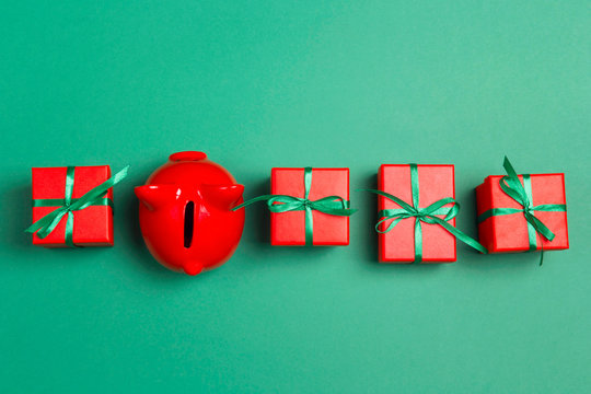 Piggy bank and christmas gifts on green background.