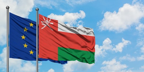 European Union and Oman flag waving in the wind against white cloudy blue sky together. Diplomacy concept, international relations.
