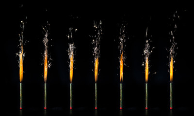 Set of burning sparklers on a black background.