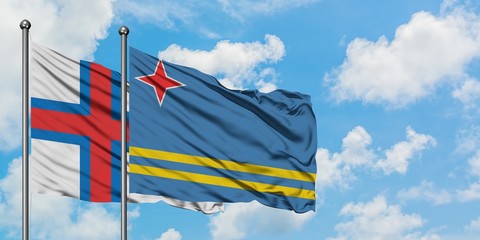 Faroe Islands and Aruba flag waving in the wind against white cloudy blue sky together. Diplomacy concept, international relations.