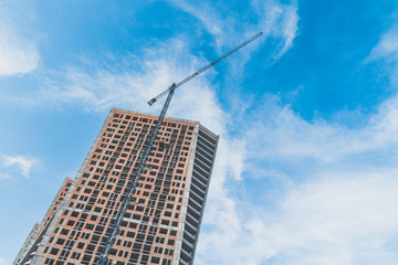 Construction of high-rise buildings in the city with tower crane with lifting boom in daytime