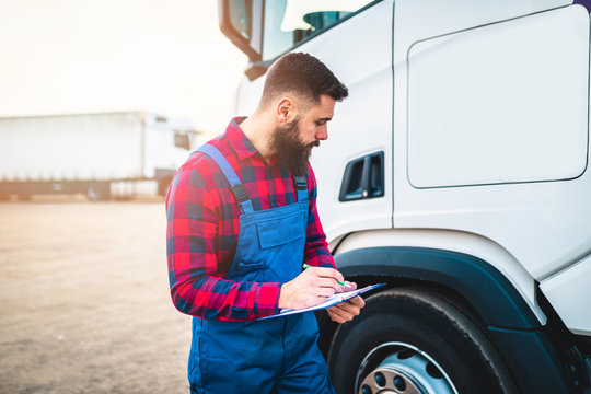 Truck Inspection And Safety. Bearded Truck Driver Daily Checking The Semi Truck Trailer.