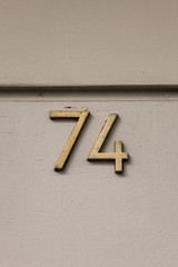 brass number 74 on white wall