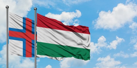 Faroe Islands and Hungary flag waving in the wind against white cloudy blue sky together. Diplomacy concept, international relations.