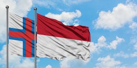 Faroe Islands and Indonesia flag waving in the wind against white cloudy blue sky together. Diplomacy concept, international relations.
