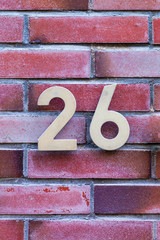 brass number 26 on brick wall