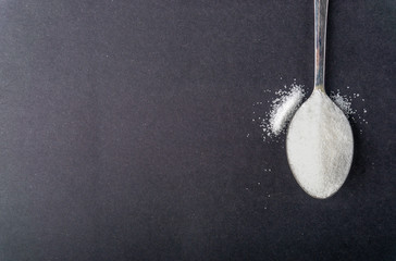 Minimalist flat lay composition sugar and spoon on the dark background. Medical, Healthcare and...