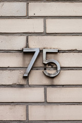 tarnished number 75 on white tile wall