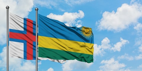 Faroe Islands and Rwanda flag waving in the wind against white cloudy blue sky together. Diplomacy concept, international relations.