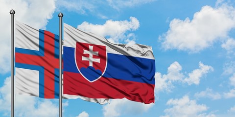 Faroe Islands and Slovakia flag waving in the wind against white cloudy blue sky together. Diplomacy concept, international relations.