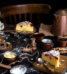 homemade tasty biscuit cake with cherries, almond flakes, powdered sugar on top