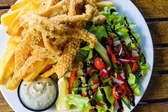 Salt And Pepper Calamari With Vegetable Salad And Potato Chips, Close Up.