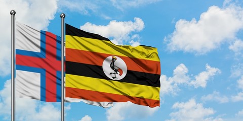 Faroe Islands and Uganda flag waving in the wind against white cloudy blue sky together. Diplomacy concept, international relations.