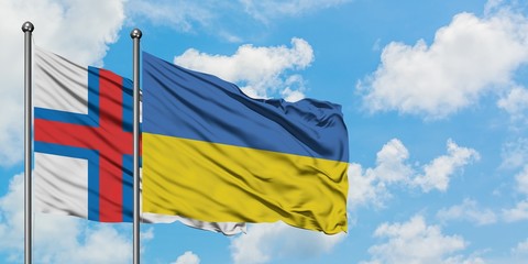 Faroe Islands and Ukraine flag waving in the wind against white cloudy blue sky together. Diplomacy concept, international relations.