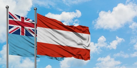Fiji and Austria flag waving in the wind against white cloudy blue sky together. Diplomacy concept, international relations.