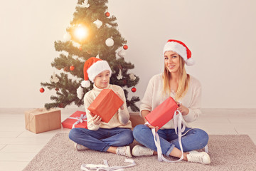 Obraz na płótnie Canvas Single parent and holidays concept - Portrait of mother and son celebrating christmas at home on christmas eve