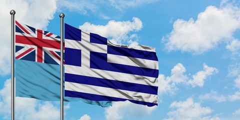 Fiji and Greece flag waving in the wind against white cloudy blue sky together. Diplomacy concept, international relations.