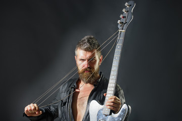 Music hobby. Guitar player in jacket with electric guitar. Rock or punk music concert. Bearded man...