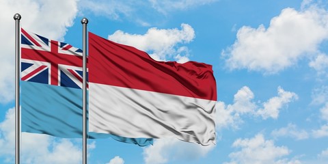 Fiji and Indonesia flag waving in the wind against white cloudy blue sky together. Diplomacy concept, international relations.