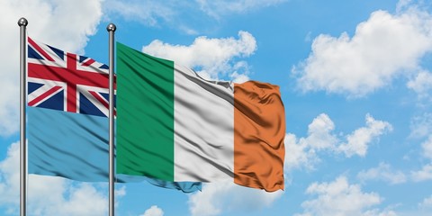 Fiji and Ireland flag waving in the wind against white cloudy blue sky together. Diplomacy concept, international relations.