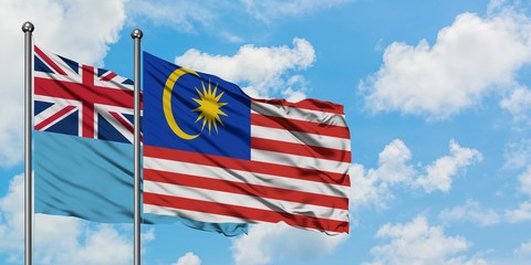 Fiji and Malaysia flag waving in the wind against white cloudy blue sky together. Diplomacy concept, international relations.