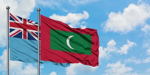 Fiji and Maldives flag waving in the wind against white cloudy blue sky together. Diplomacy concept, international relations.
