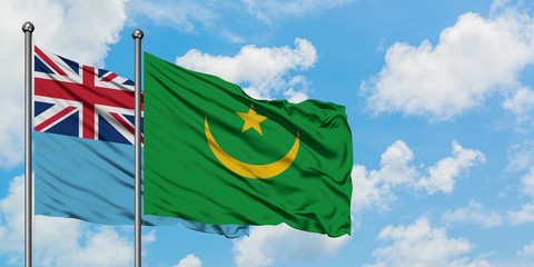 Fiji and Mauritania flag waving in the wind against white cloudy blue sky together. Diplomacy concept, international relations.