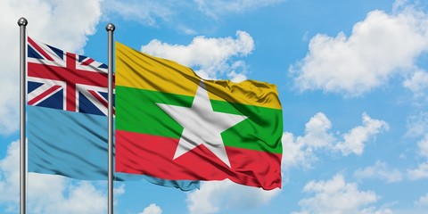 Fiji and Myanmar flag waving in the wind against white cloudy blue sky together. Diplomacy concept, international relations.