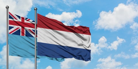 Fiji and Netherlands flag waving in the wind against white cloudy blue sky together. Diplomacy concept, international relations.