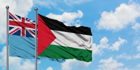 Fiji and Palestine flag waving in the wind against white cloudy blue sky together. Diplomacy concept, international relations.