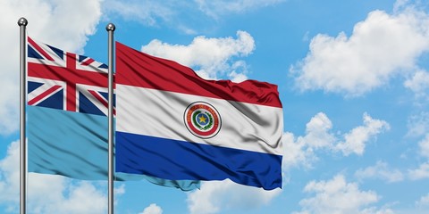 Fiji and Paraguay flag waving in the wind against white cloudy blue sky together. Diplomacy concept, international relations.