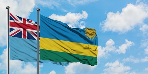 Fiji and Rwanda flag waving in the wind against white cloudy blue sky together. Diplomacy concept, international relations.