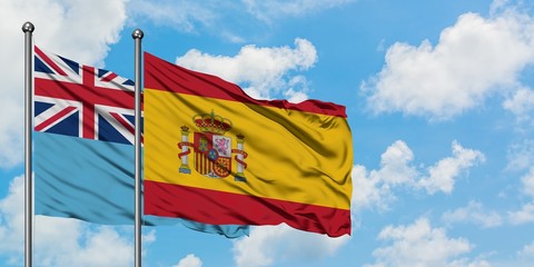 Fiji and Spain flag waving in the wind against white cloudy blue sky together. Diplomacy concept, international relations.