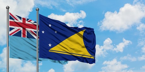 Fiji and Tokelau flag waving in the wind against white cloudy blue sky together. Diplomacy concept, international relations.