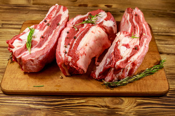 Raw pork ribs with spices and rosemary on wooden table