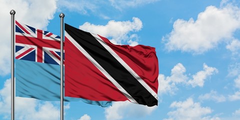 Fiji and Trinidad And Tobago flag waving in the wind against white cloudy blue sky together. Diplomacy concept, international relations.