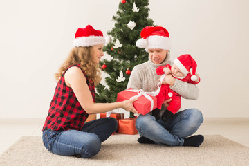 Obraz na płótnie Canvas Happy couple with baby celebrating Christmas together at home.